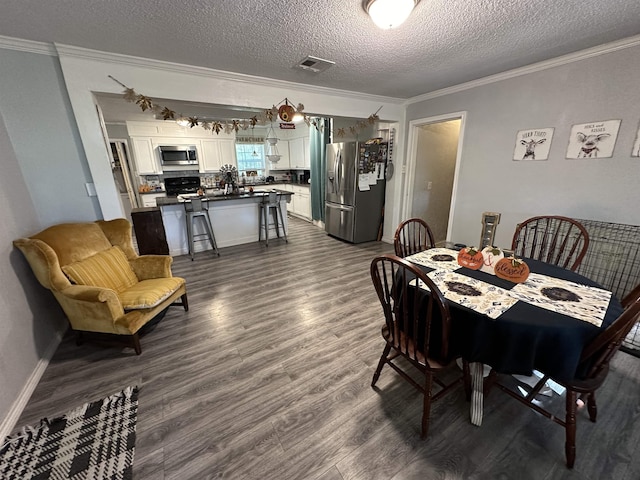 dining space featuring dark hardwood / wood-style flooring, a textured ceiling, and ornamental molding