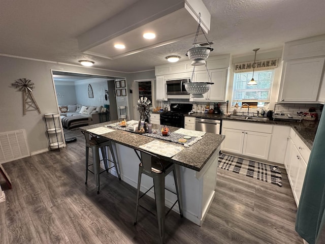 kitchen featuring sink, a kitchen island, a kitchen breakfast bar, white cabinets, and appliances with stainless steel finishes