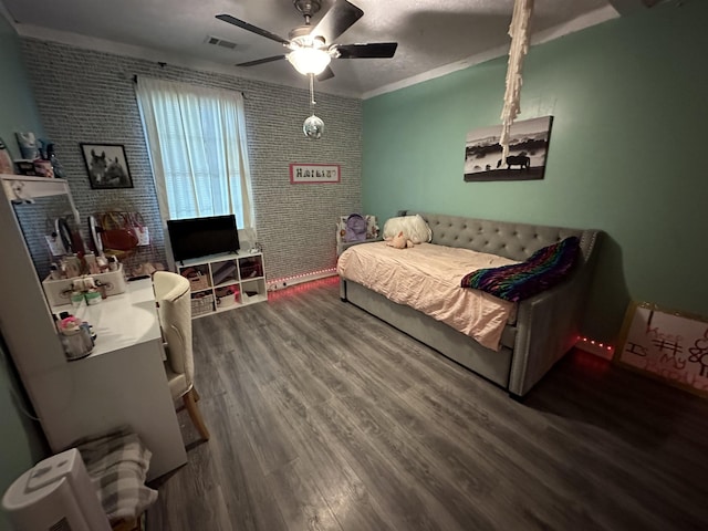 bedroom featuring ceiling fan, wood-type flooring, crown molding, and brick wall