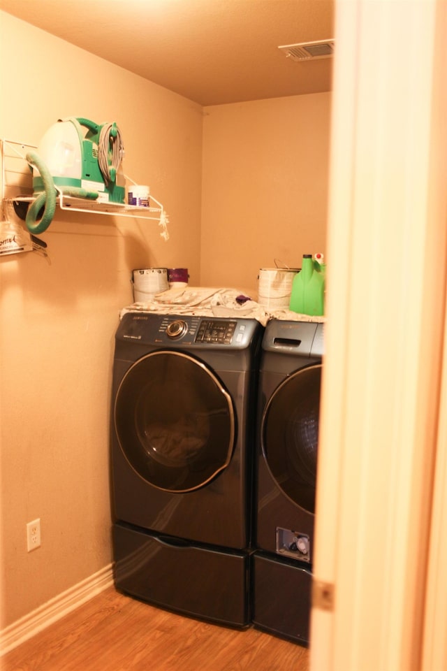 clothes washing area with hardwood / wood-style flooring and independent washer and dryer