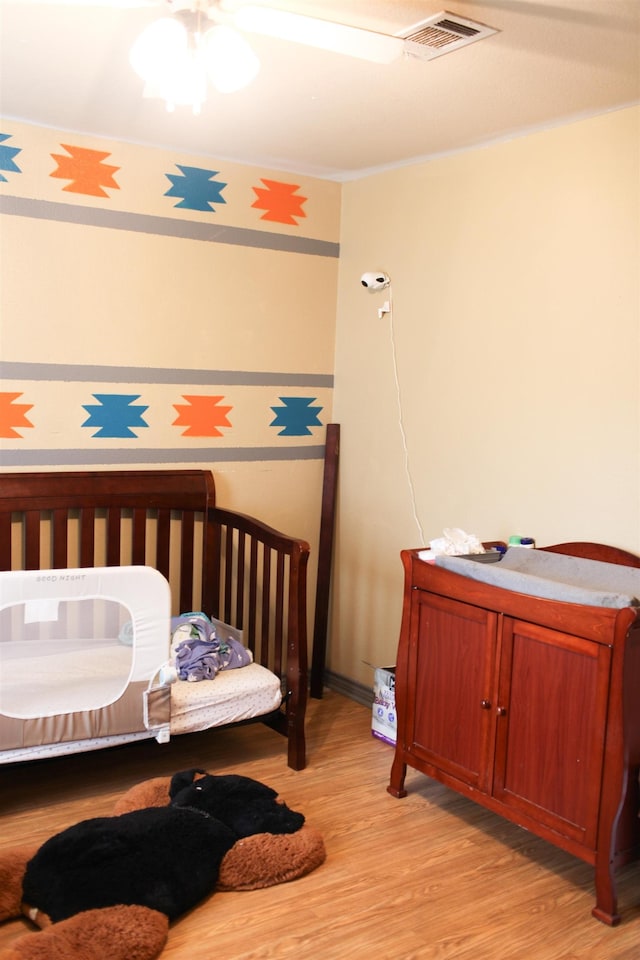 bedroom featuring a nursery area and light hardwood / wood-style flooring