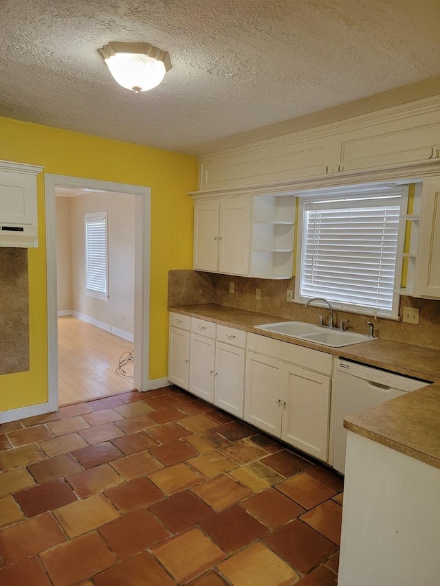 kitchen featuring backsplash, a textured ceiling, white dishwasher, sink, and white cabinets