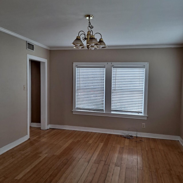 unfurnished room with crown molding, hardwood / wood-style floors, and a chandelier