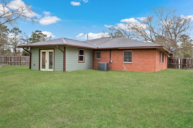 back of property featuring brick siding, a fenced backyard, cooling unit, and a yard