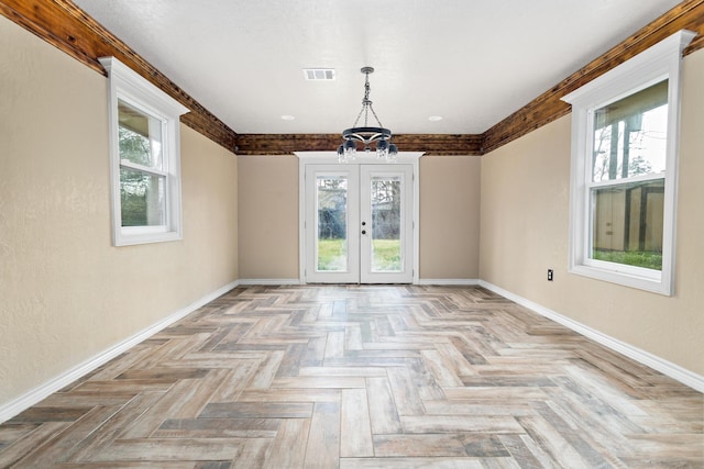 empty room with a healthy amount of sunlight, a notable chandelier, visible vents, and baseboards