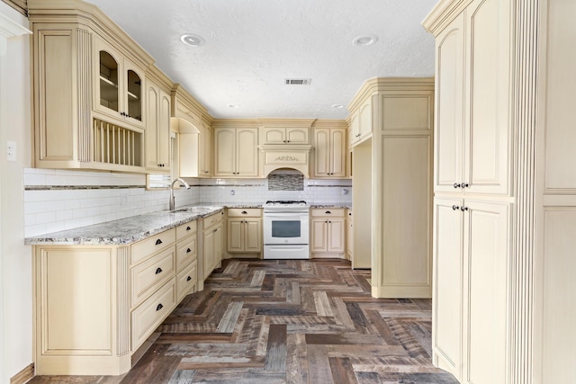 kitchen featuring cream cabinets, a sink, and white range with gas stovetop