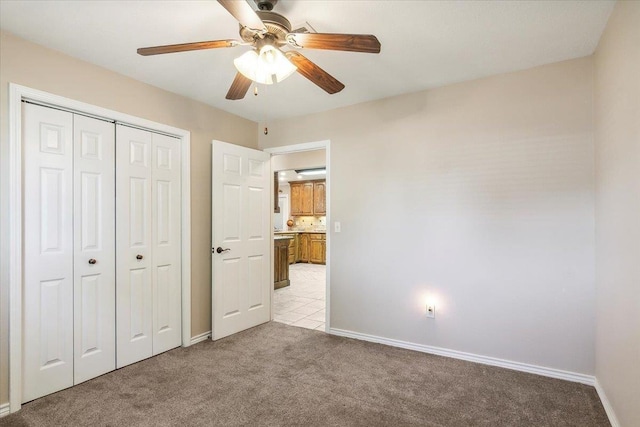 unfurnished bedroom featuring ceiling fan, a closet, and light colored carpet