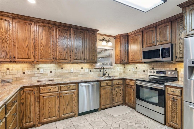 kitchen with light stone countertops, appliances with stainless steel finishes, backsplash, and sink