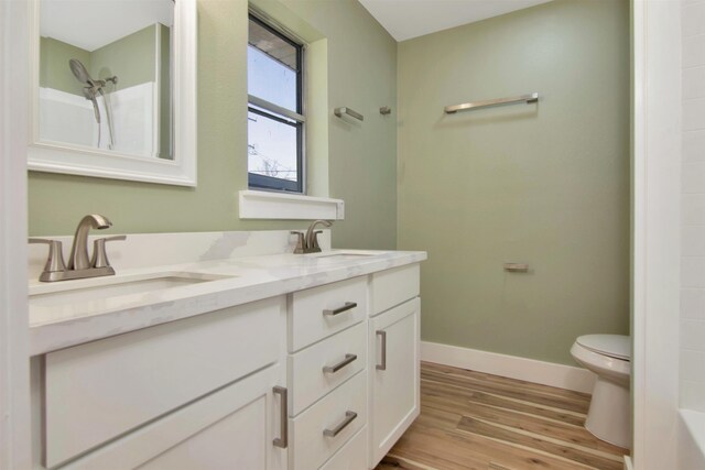1105 W Dr, Port Neches, TX 77651 - bathroom with toilet, double vanity, wood finished floors, and baseboards