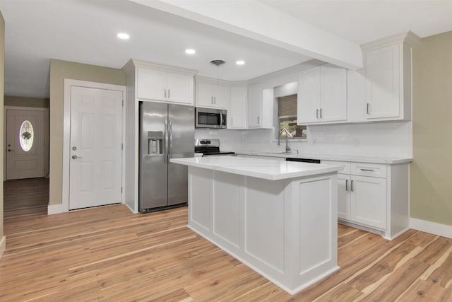 1105 W Dr, Port Neches, TX 77651 - kitchen featuring stainless steel appliances, white cabinetry, light countertops, a center island, and light wood-type flooring