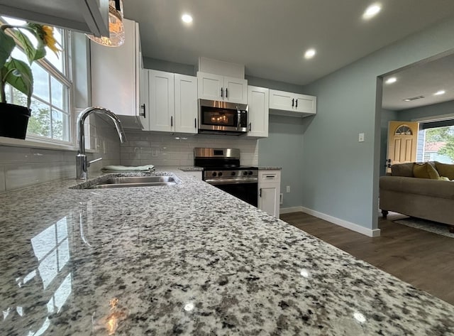 kitchen with white cabinets, stainless steel appliances, light stone countertops, and sink