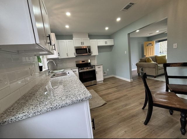 kitchen featuring decorative backsplash, light stone counters, stainless steel appliances, sink, and white cabinets