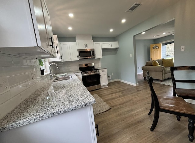 kitchen with sink, decorative backsplash, light stone countertops, appliances with stainless steel finishes, and white cabinetry