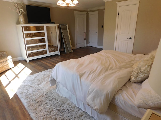 bedroom featuring an inviting chandelier, crown molding, baseboards, and wood finished floors