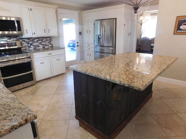 kitchen featuring decorative backsplash, light stone counters, appliances with stainless steel finishes, crown molding, and white cabinetry