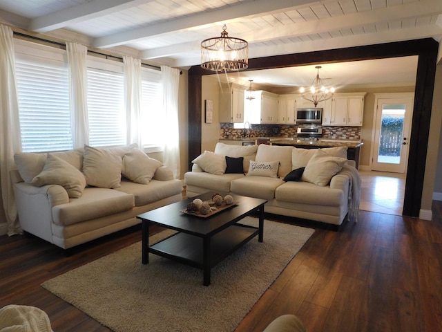 living room with dark wood-style floors, a wealth of natural light, beam ceiling, and a notable chandelier