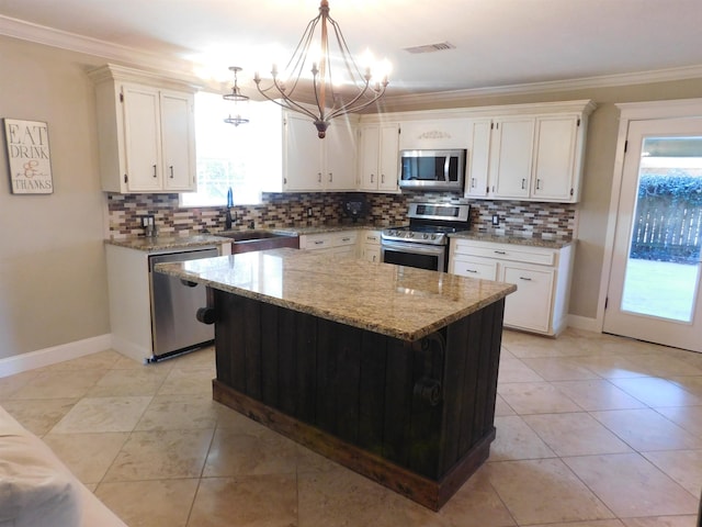 kitchen featuring stainless steel appliances, a sink, visible vents, decorative backsplash, and crown molding