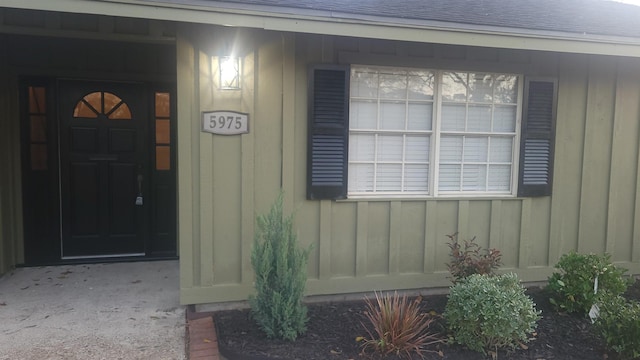 property entrance with board and batten siding and roof with shingles