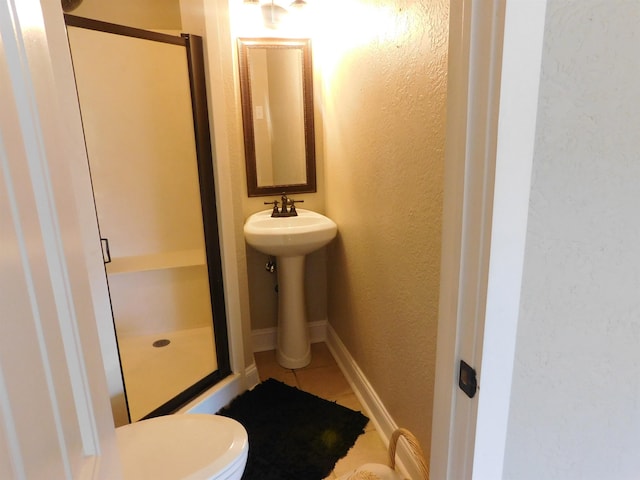 full bath featuring a stall shower, tile patterned flooring, a textured wall, and baseboards