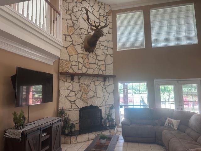 10994 Bessie Heights Rd, Orange, TX 77630 - tiled living room featuring a stone fireplace, french doors, a towering ceiling, and ornamental molding