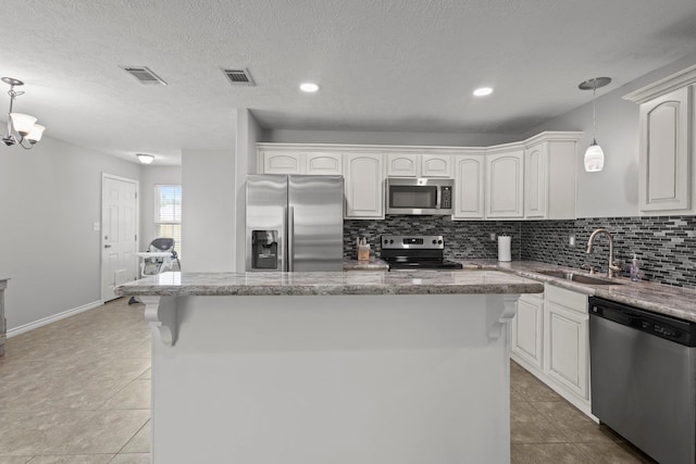 6605 Palace Dr, Lumberton, TX 77657 - kitchen featuring stainless steel appliances, a sink, decorative backsplash, hanging light fixtures, and a center island