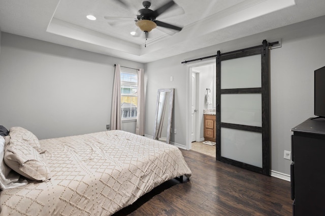 6605 Palace Dr, Lumberton, TX 77657 - bedroom featuring a raised ceiling, a barn door, dark wood-type flooring, recessed lighting, and baseboards