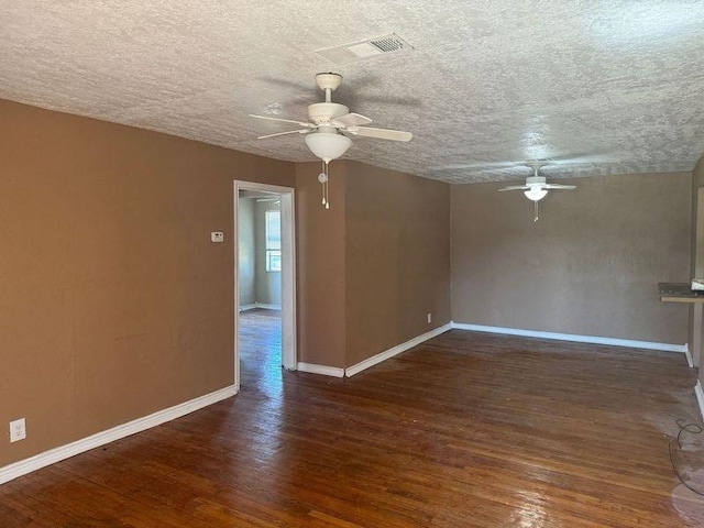 empty room with dark hardwood / wood-style floors, ceiling fan, and a textured ceiling