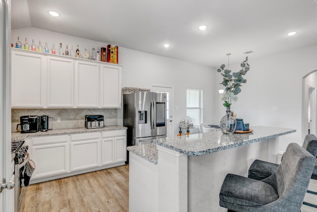 1560 Alice Dr, Beaumont, TX 77705 - kitchen with stainless steel appliances, arched walkways, a kitchen breakfast bar, white cabinetry, and backsplash