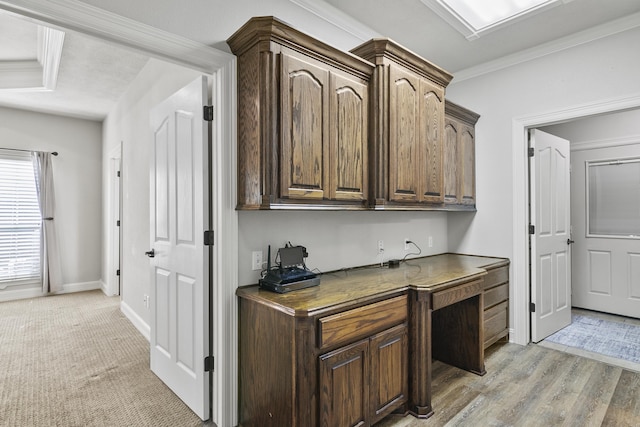 bar with crown molding, built in desk, light hardwood / wood-style floors, and dark brown cabinets