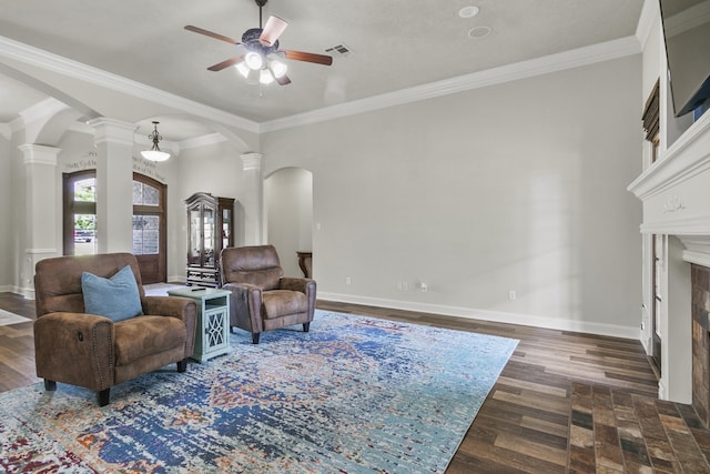 living room featuring dark hardwood / wood-style flooring, ornamental molding, ceiling fan, and ornate columns