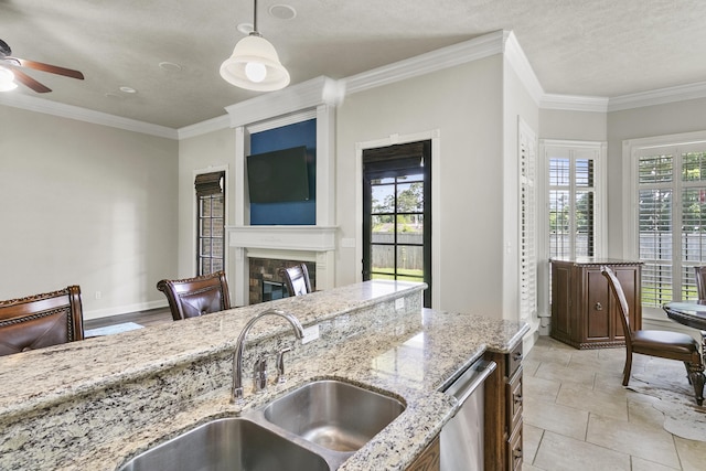 kitchen featuring a healthy amount of sunlight, light stone countertops, sink, and pendant lighting