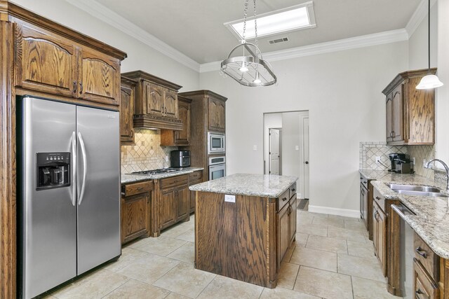 kitchen featuring pendant lighting, sink, crown molding, appliances with stainless steel finishes, and a kitchen island