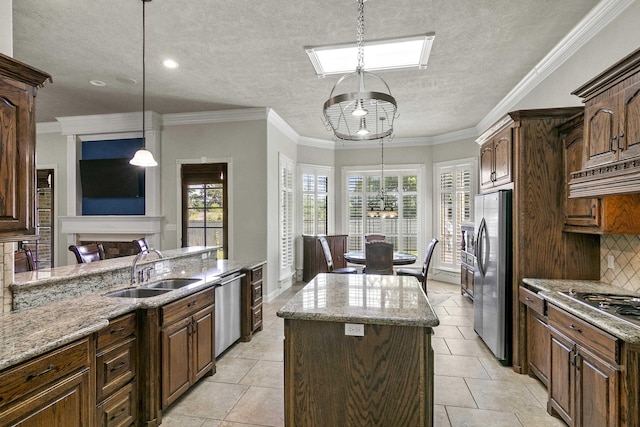 kitchen with extractor fan, sink, decorative light fixtures, appliances with stainless steel finishes, and a kitchen island