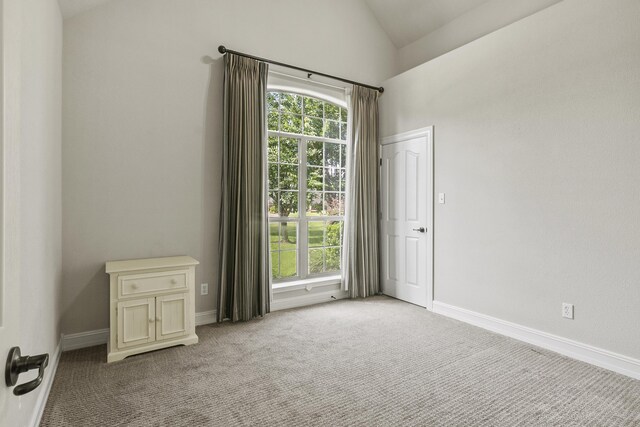 empty room with lofted ceiling and light carpet