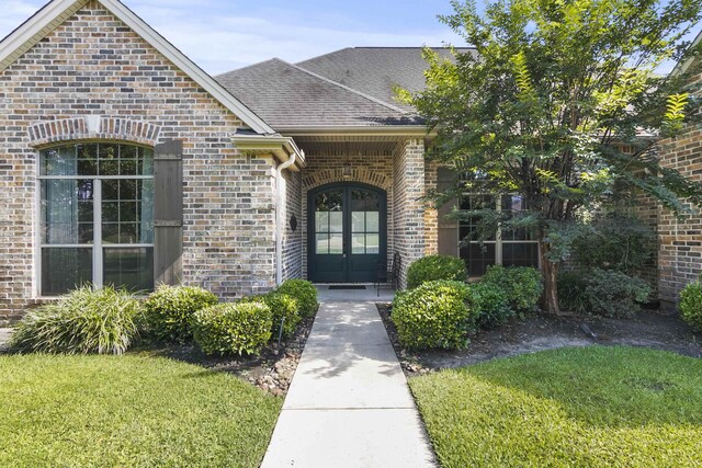 view of exterior entry featuring a lawn and french doors