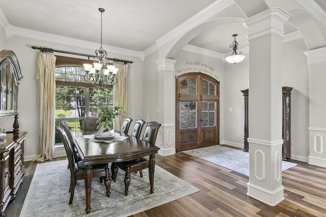 dining area with dark wood-type flooring, crown molding, decorative columns, and a notable chandelier