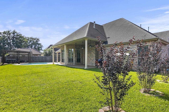 back of property with a fenced in pool, a patio, and a lawn