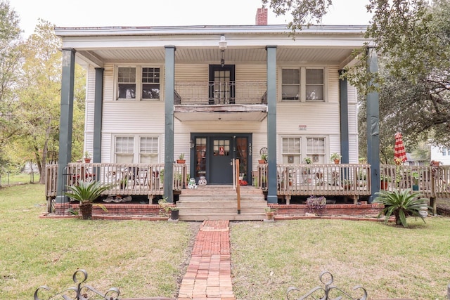 view of front of house featuring a balcony and a front lawn