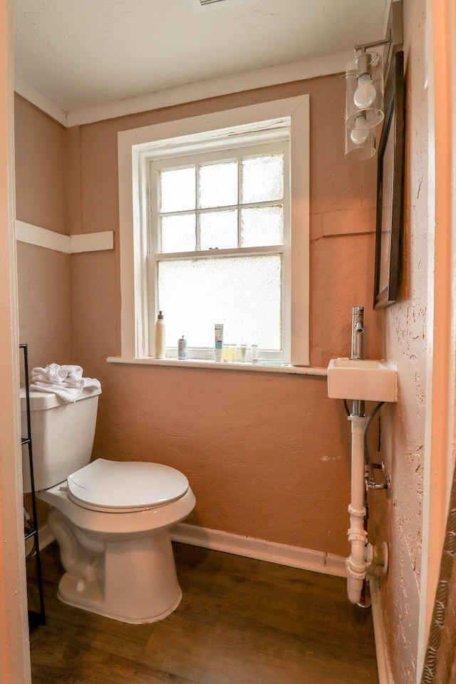 bathroom with toilet, wood-type flooring, and ornamental molding