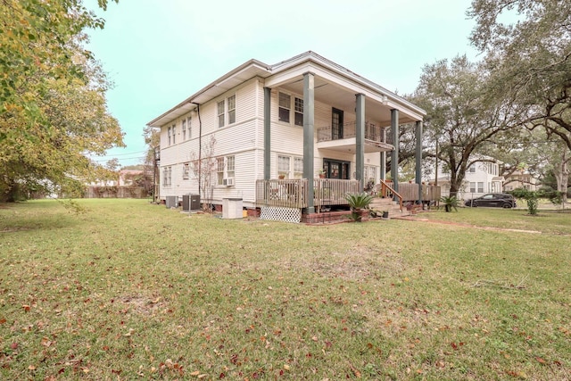 rear view of property with a balcony, cooling unit, and a lawn