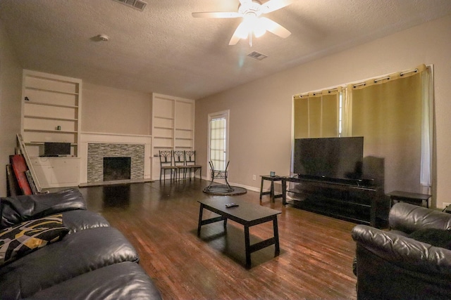 living room with a fireplace, ceiling fan, dark hardwood / wood-style flooring, and a textured ceiling