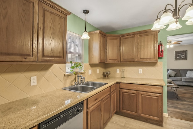 kitchen featuring sink, stainless steel dishwasher, pendant lighting, ceiling fan with notable chandelier, and light wood-type flooring