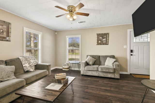 living room featuring a healthy amount of sunlight, crown molding, ceiling fan, and dark wood-type flooring