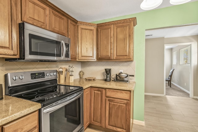 kitchen with decorative backsplash, light stone counters, and stainless steel appliances