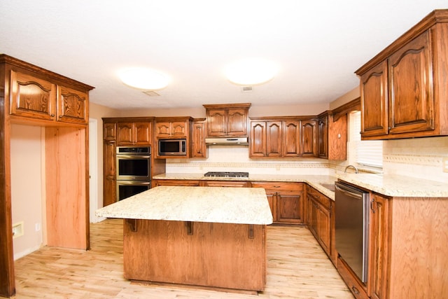 kitchen with a center island, tasteful backsplash, appliances with stainless steel finishes, a sink, and under cabinet range hood