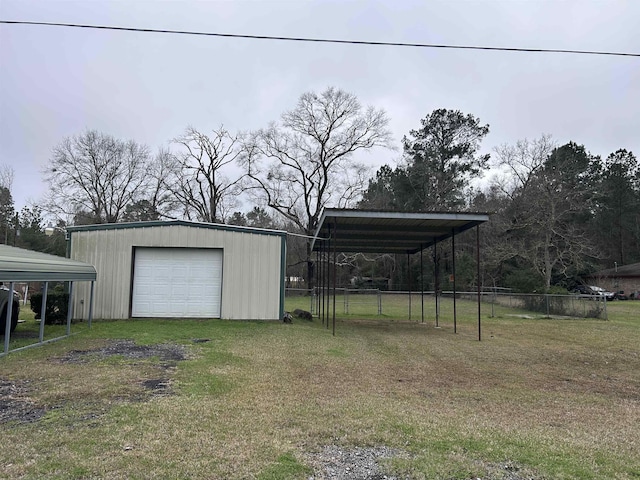 view of yard with a garage, an outdoor structure, fence, driveway, and a carport