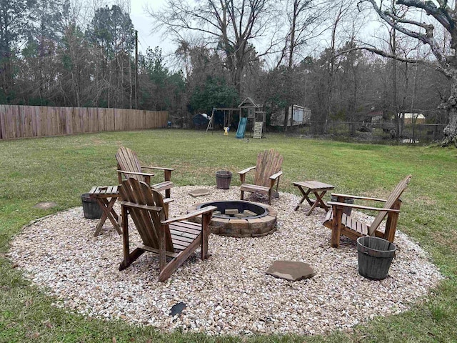 view of yard with fence, a fire pit, and a playground