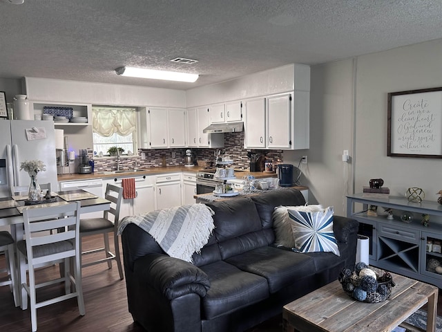 living area with a textured ceiling, dark wood finished floors, and visible vents