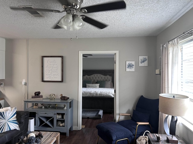 interior space with ceiling fan, a textured ceiling, visible vents, and dark wood-type flooring