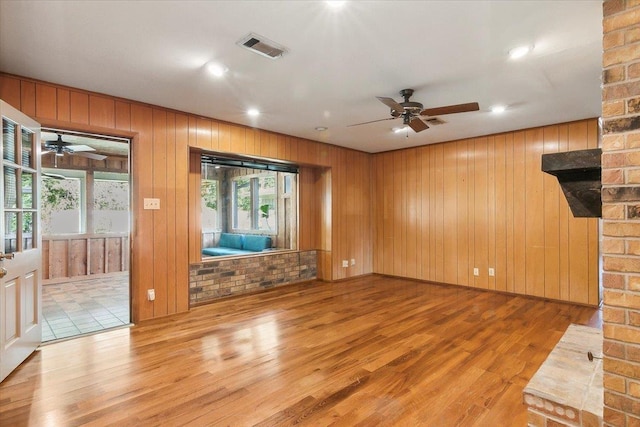 unfurnished living room featuring a fireplace, ceiling fan, plenty of natural light, and light hardwood / wood-style floors